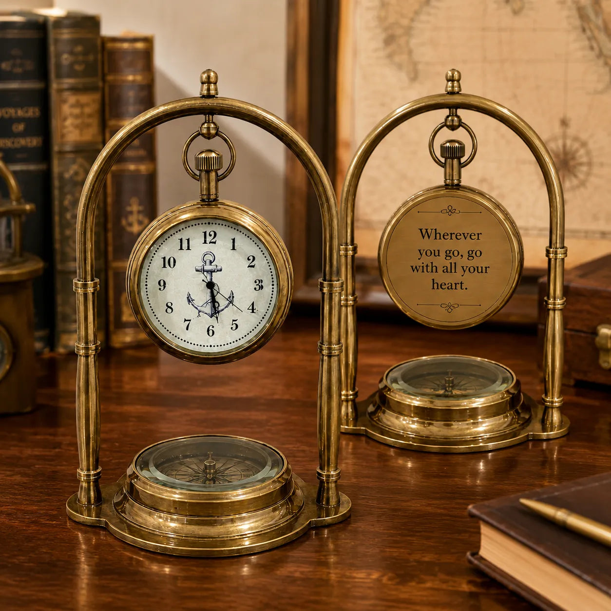 A brass nautical clock and compass table decor set on a wooden desk, styled with vintage books and a map in the background. The left component features a round clock with an anchor face, while the right component is engraved with the quote 'Wherever you go, go with all your heart.