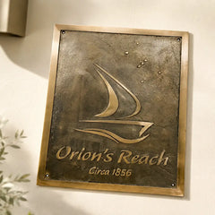 Close-up of personalized bronze plaque reading Orion’s Reach on a pale stone wall