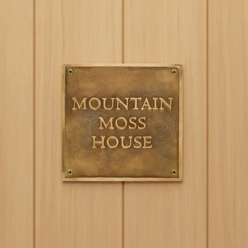 Brass plaque with 'Mountain Moss House' on a wooden wall
