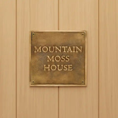 Brass plaque with 'Mountain Moss House' on a wooden wall