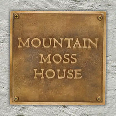 Antique Brass plaque with 'Mountain Moss House' text on a stone wall background