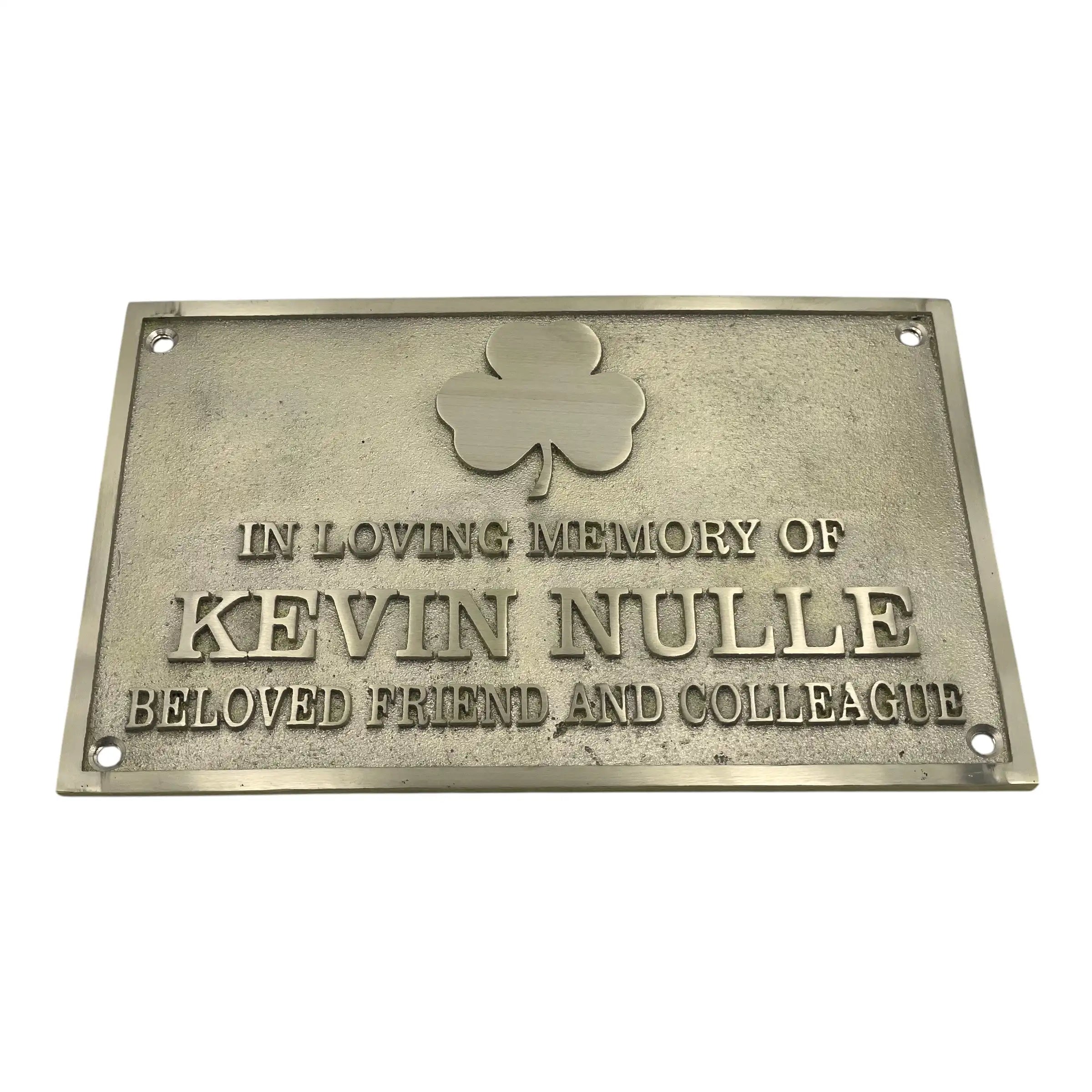 Memorial plaque with a shamrock symbol and text on a white background