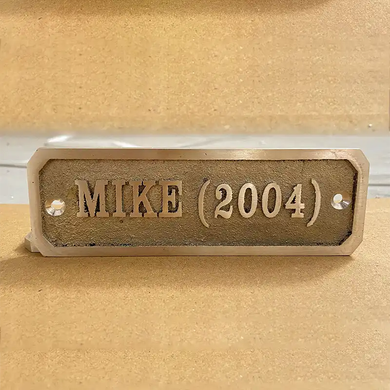 Metal nameplate with 'CUSTOM TEXT ' engraved on a beige background