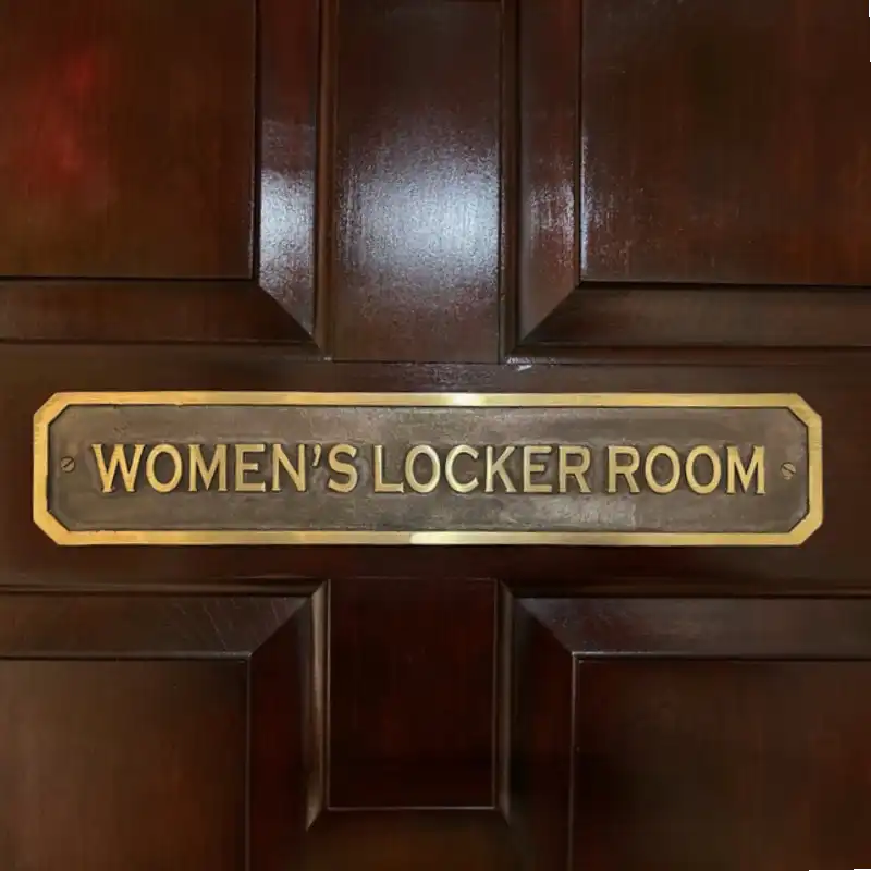 Wooden door with a gold 'WOMEN'S LOCKER ROOM' Brass Door Sign