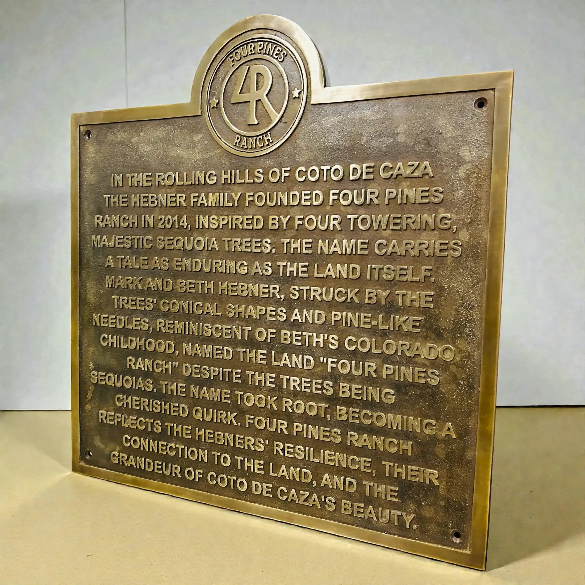 Bronze plaque with engraved text and Four Pines Ranch logo on a white background