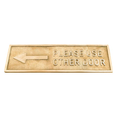 Brass metal door sign with an arrow and text 'Please Use Other Door' on a white background