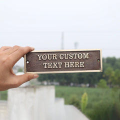 Hand holding a customizable nameplate with 'Your Custom Text Here' text against a blurred outdoor background.