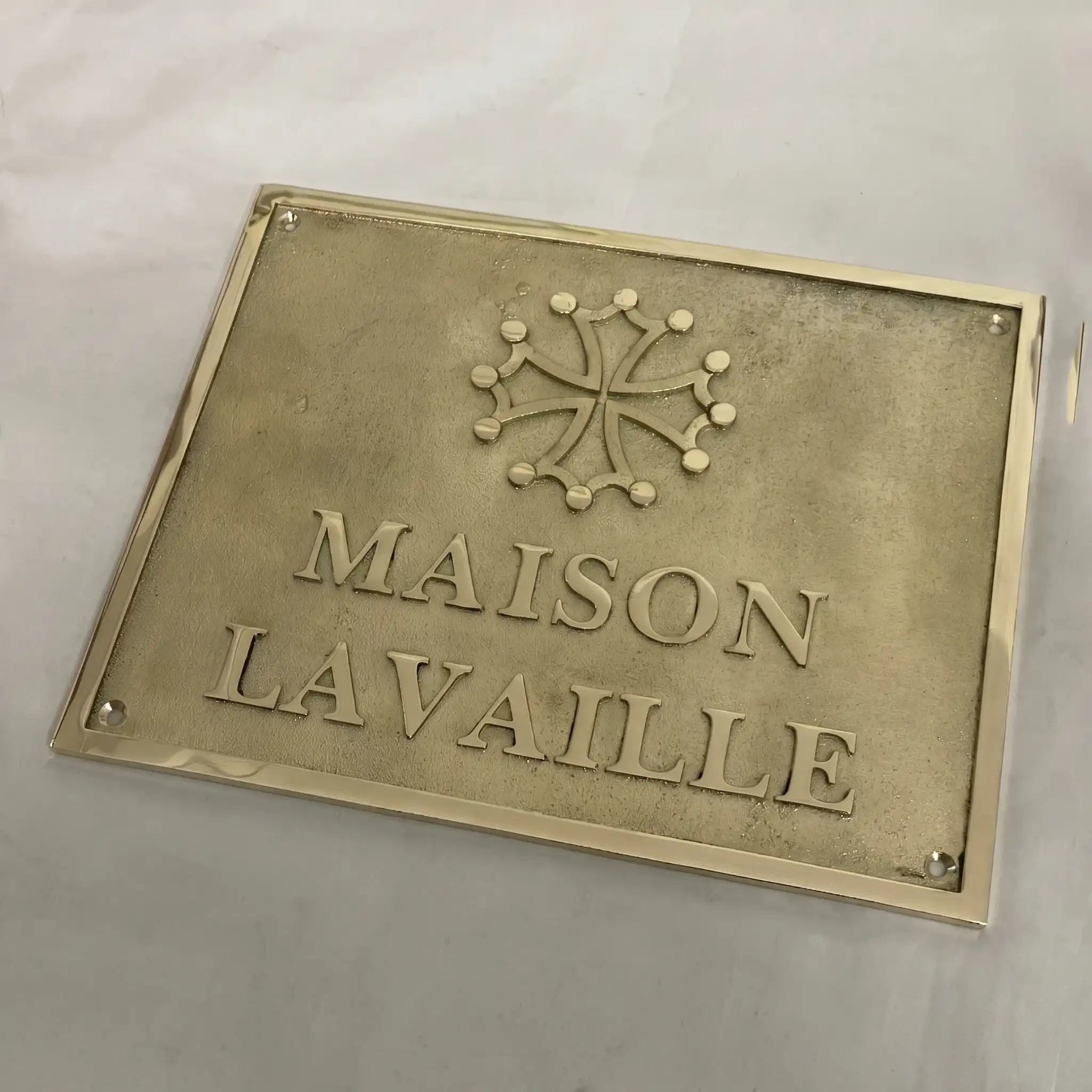 Brass plaque with 'MAISON LAVALLE' text and emblem on a light gray background