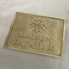 Brass plaque with 'MAISON LAVALLE' text and emblem on a light gray background