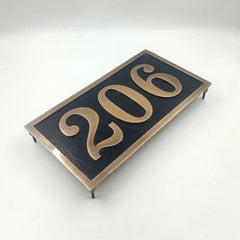 Rectangular address sign with '206' in gold on a black background