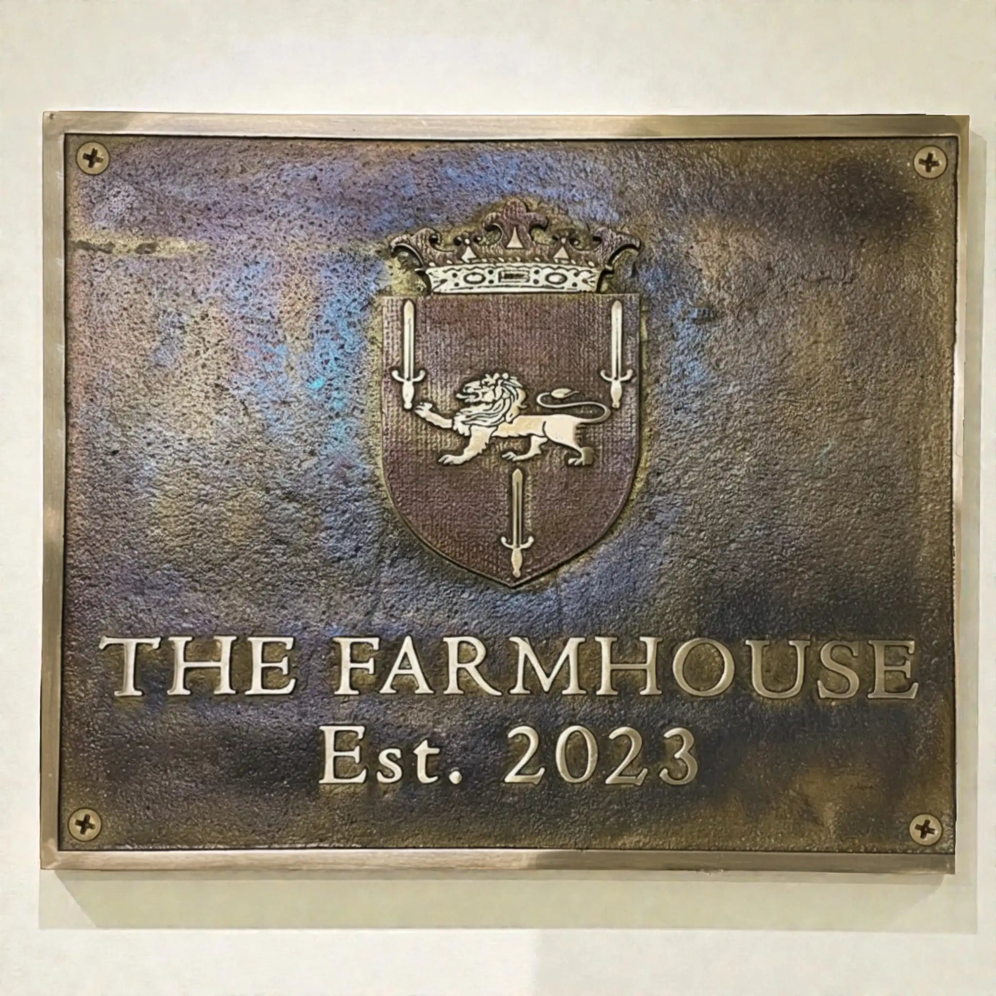 Brass address plaque with a lion emblem and text 'The Farmhouse Est. 2023' on a textured background