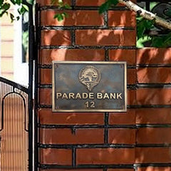Decorative metal plaque with 'Parade Bank 12' on a brick wall background