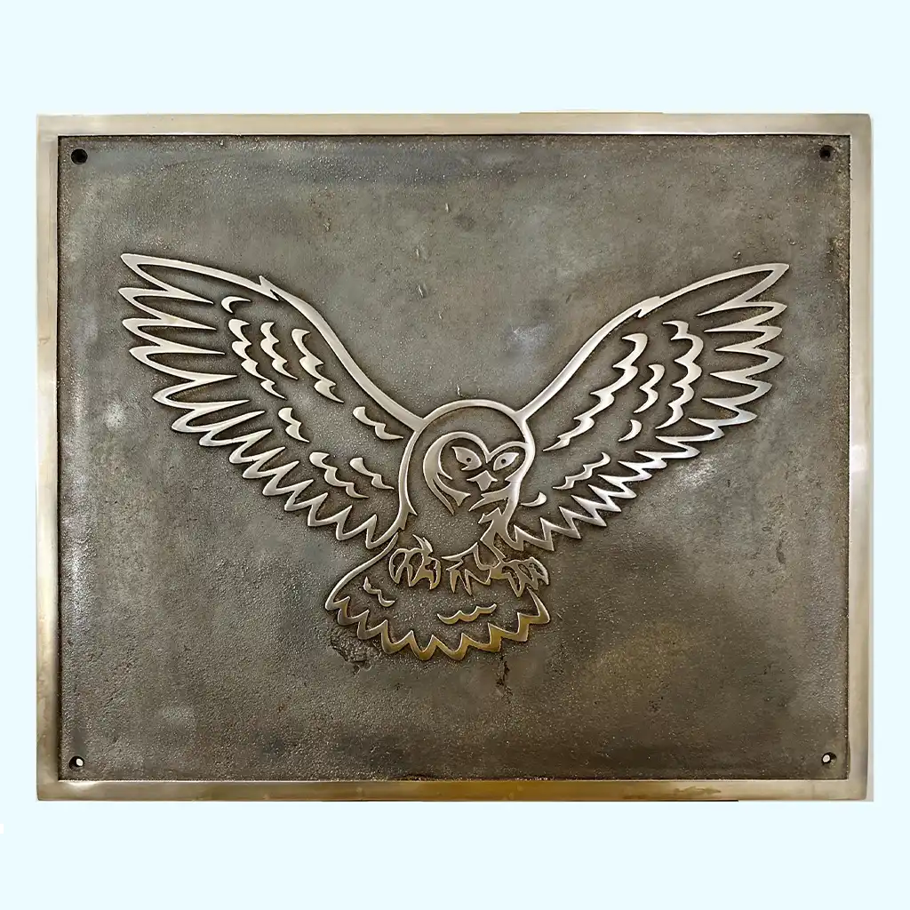 Heritage-style bronze metal plaque with an embossed owl design on a textured background