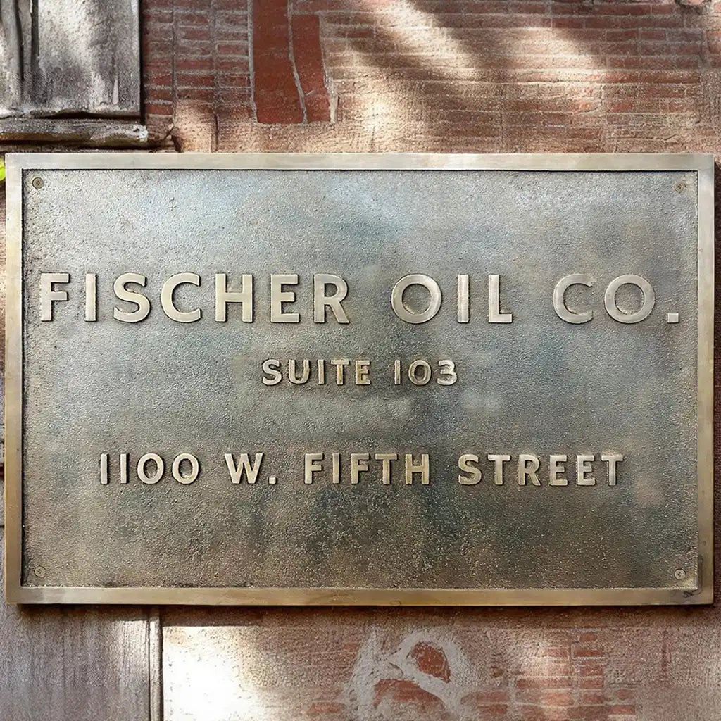 Old-world bronze sign Metal sign for Fischer Oil Co. on a brick wall