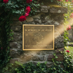 Bronze Memorial plaque on a stone wall with red flowers