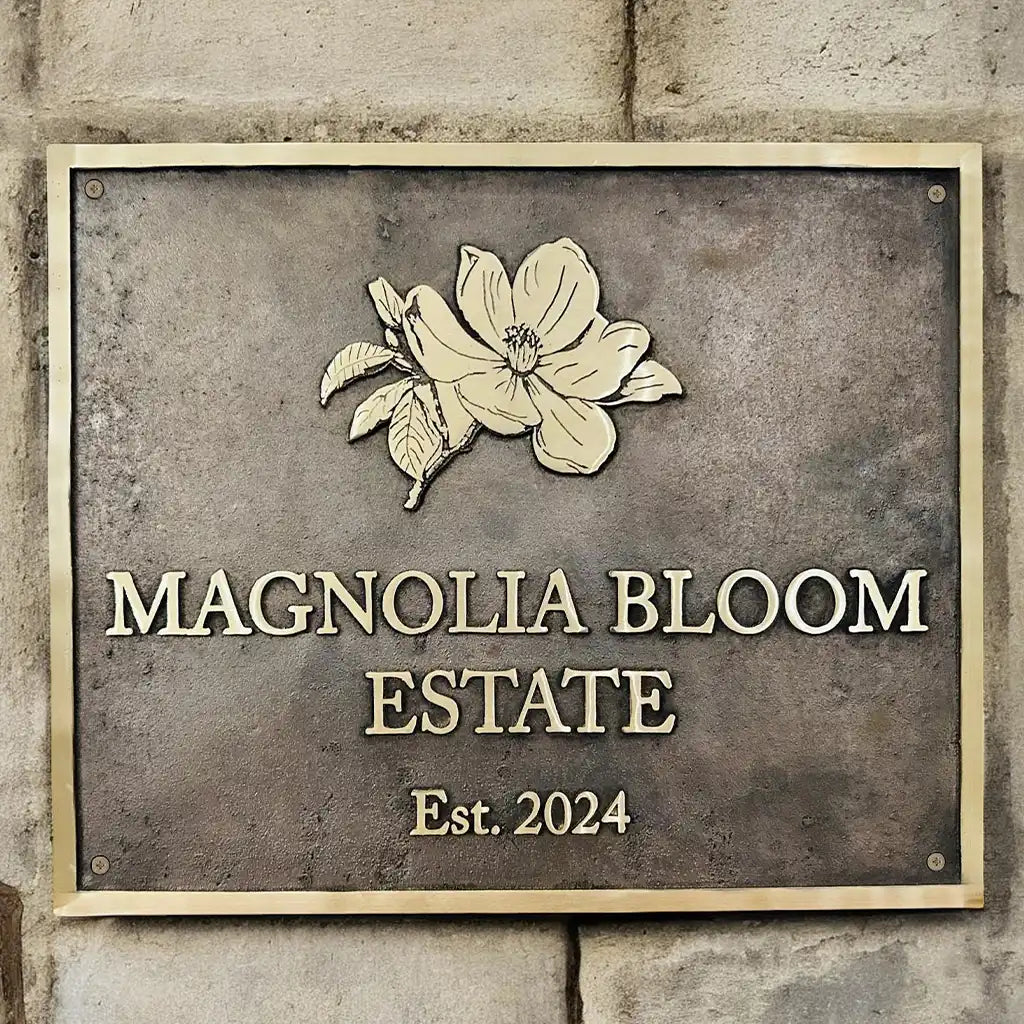 Custom bronze address sign with floral design on a stone wall.