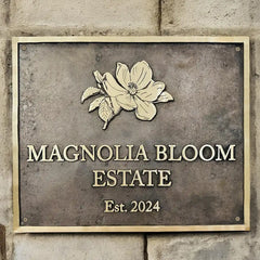 Custom bronze address sign with floral design on a stone wall.