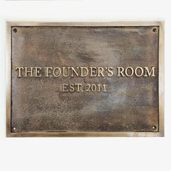Bronze plaque with 'The Founder's Room EST 2011' text on a white background