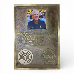 Bronze memorial plaque with engraved text and a photo of a man, on a white background