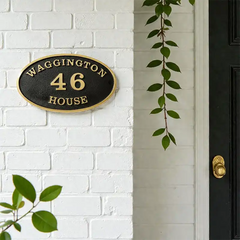 House number sign on a white brick wall with a black door.