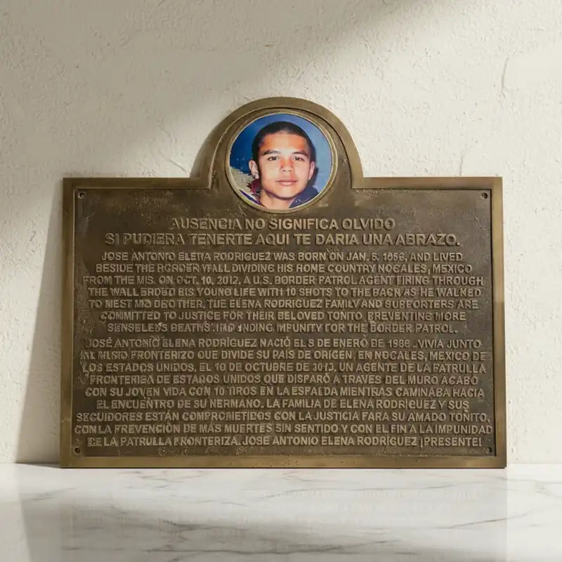 Bronze plaque with a photo of a man and text on a white marble surface