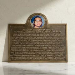 Bronze plaque with a photo of a man and text on a white marble surface