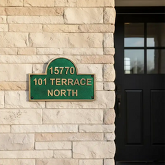 Green address sign on a stone wall next to a black door