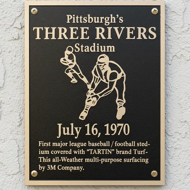 Plaque commemorating Pittsburgh's Three Rivers Stadium with a baseball player illustration and text.