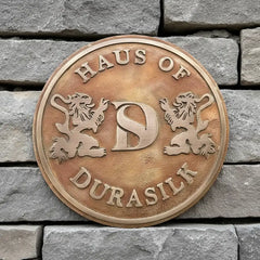 Bronze plaque with text and lion designs on a stone wall background | Bronze address plaque