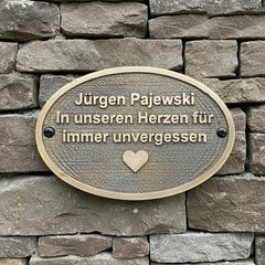 Memorial plaque with engraved text on a stone wall, Cast bronze plaque oval-shaped