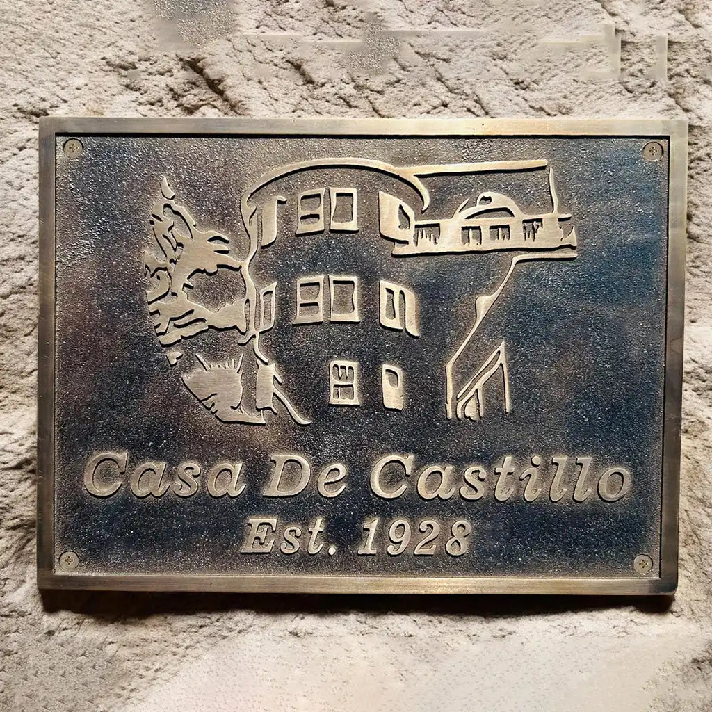Bronze plaque with 'Casa De Castillo' and establishment year on a stone wall.