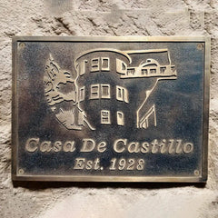Bronze plaque with 'Casa De Castillo' and establishment year on a stone wall.