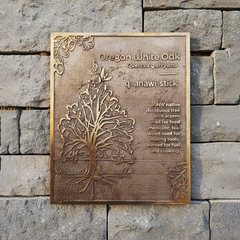 engraved bronze plaque for home with tree design and text on a stone wall
