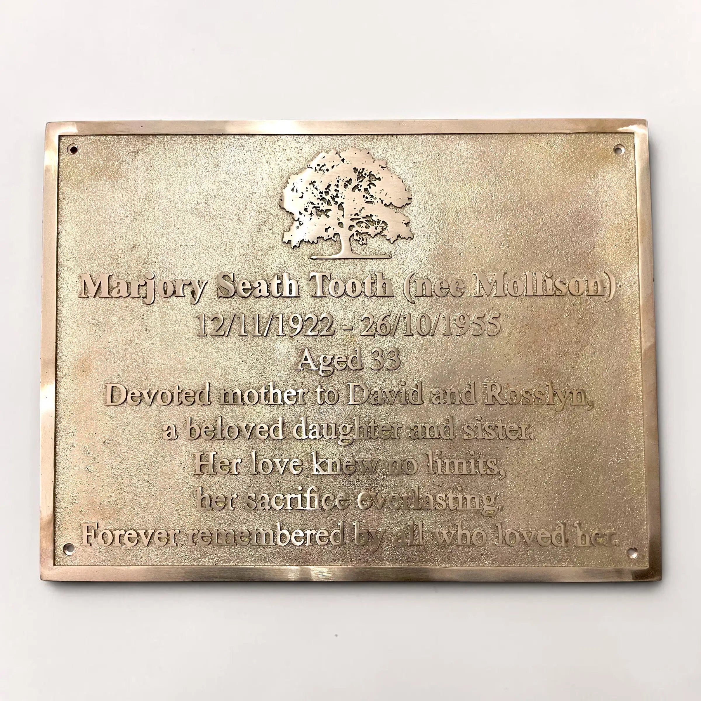 Brass plaque with engraved text and an oak tree design on a white background