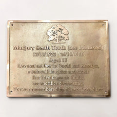 Brass plaque with engraved text and an oak tree design on a white background