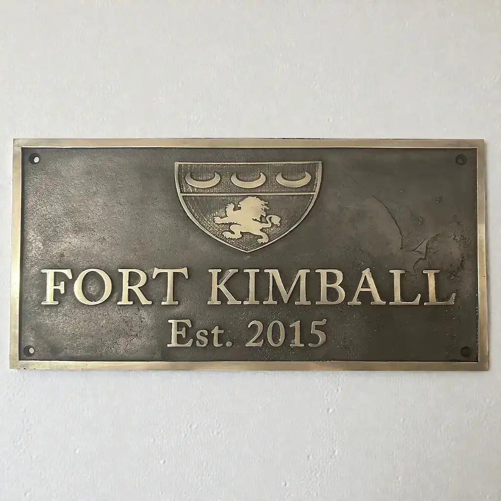 Bronze plaque with text and logo on a white wall | Bronze address plaque for house