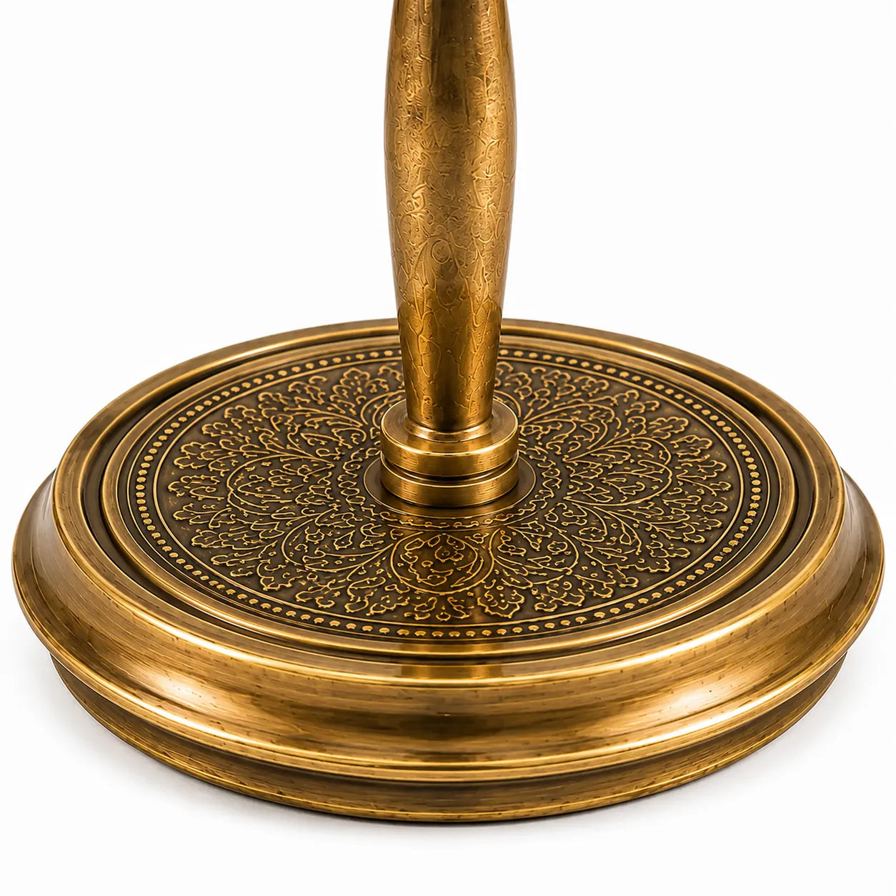 Close-up of an ornate brass table base with a circular, intricately embossed floral pattern and a central pedestal stem, shown on a white background.