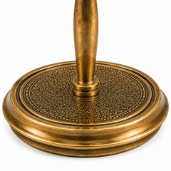 Close-up of an ornate brass table base with a circular, intricately embossed floral pattern and a central pedestal stem, shown on a white background.