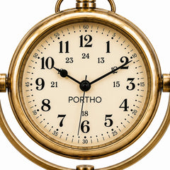 A close-up of a round analog clock with a polished gold brass case and a cream-colored dial. The clock features bold black Arabic numerals, black hands, and the brand name 'PORTHO' printed below the 12 o'clock position.