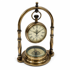 An antique-style brass mantel clock featuring a suspended pocket-watch face with Roman numerals and a compass base, photographed on a white background.