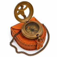 Open brass sundial compass displayed on orange leather carry pouch