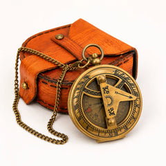 An antique brass pocket compass with a chain, displayed in front of its brown leather case on a white background.