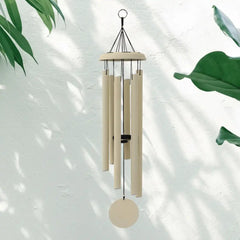 Off-White Corinthian Bells Wind Chime hanging against a light background with green leaves