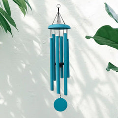 A light blue Corinthian bell wind chime hanging against a white background with green leaves.