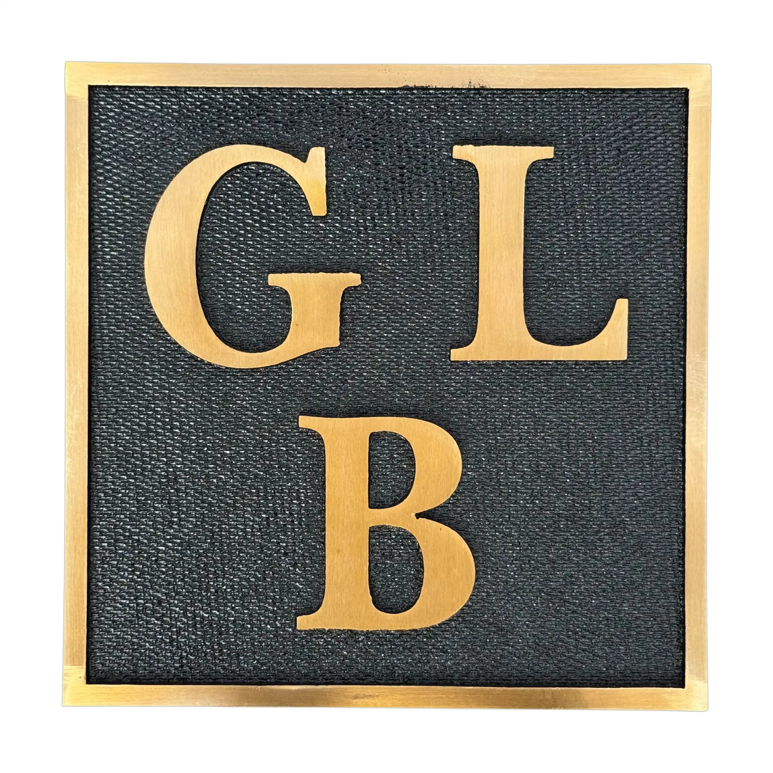 Brass plaque with gold letters 'GLB' on a white background