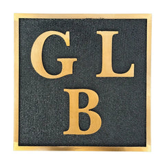 Brass plaque with gold letters 'GLB' on a white background