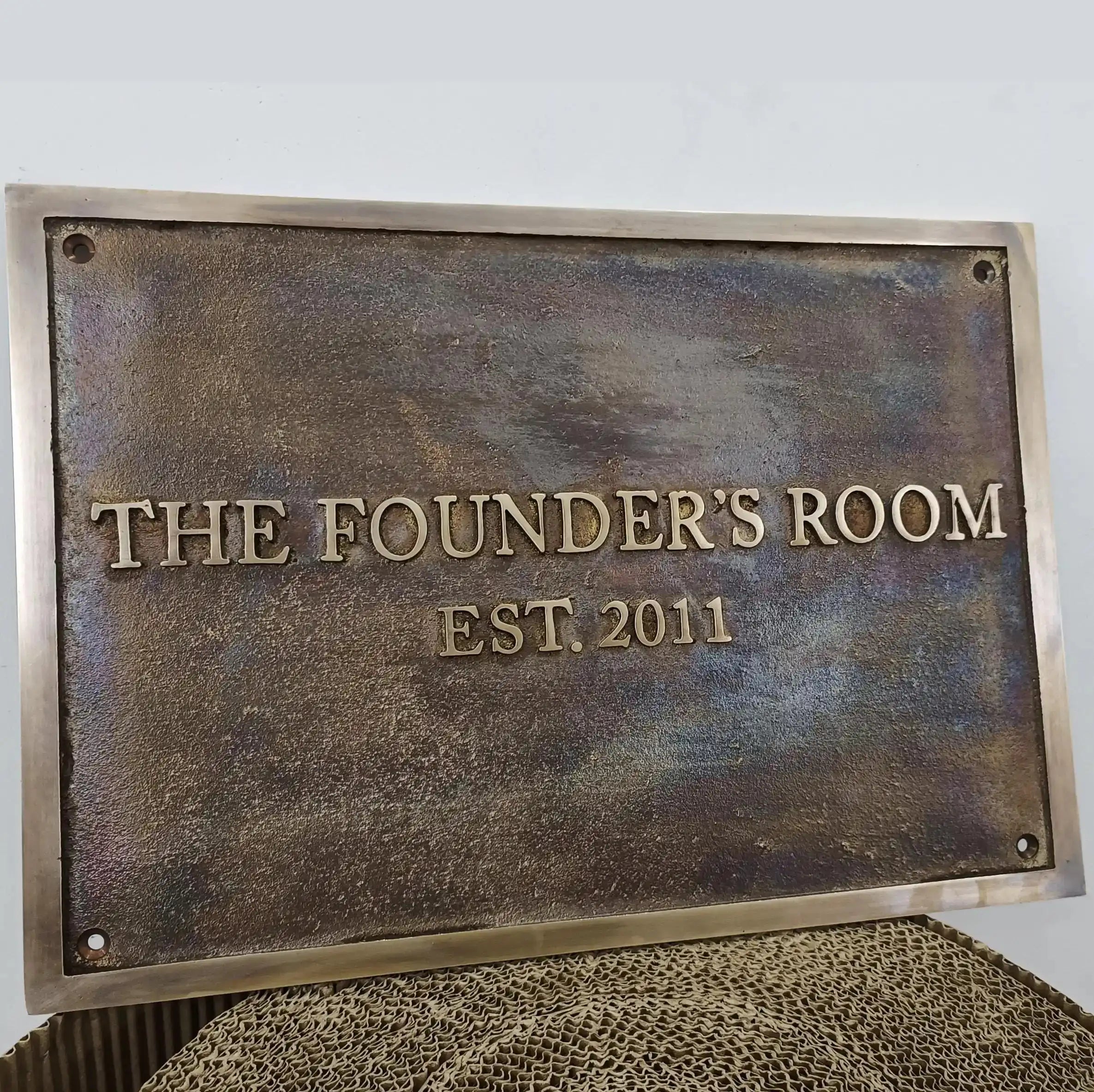 Bronze plaque with 'The Founder's Room EST. 2011' text on a light gray background