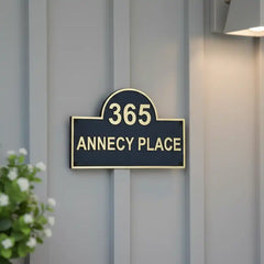 Stylish Black Finish Brass House Number Sign on a gray wall with a plant in the corner.