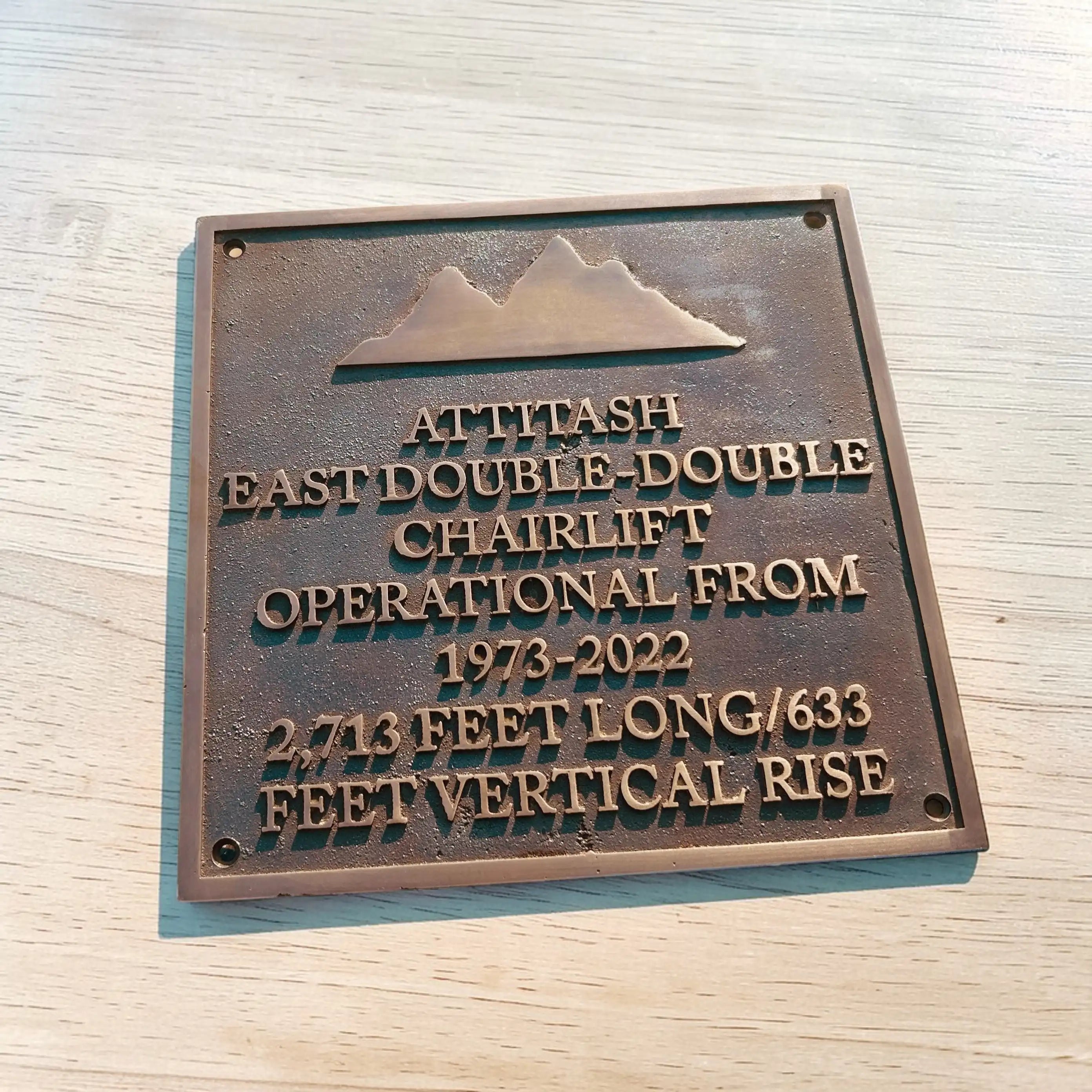 Bronze plaque with engraved text on a wooden surface