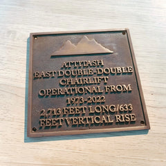 Bronze plaque with engraved text on a wooden surface